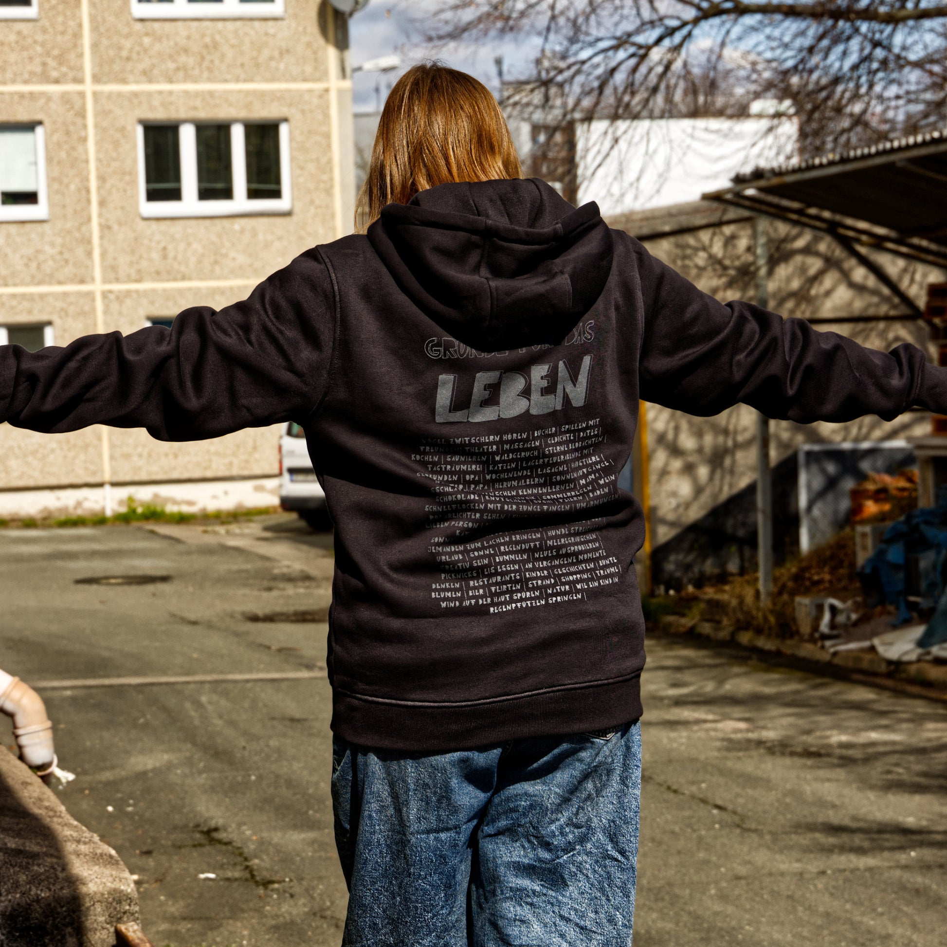 Weibliches Modell balanciert. Sie trägt einen schwarzen Hoodie mit dem handedruckten Motiv: Gründe für das leben