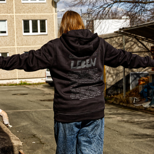 Weibliches Modell balanciert. Sie trägt einen schwarzen Hoodie mit dem handedruckten Motiv: Gründe für das leben