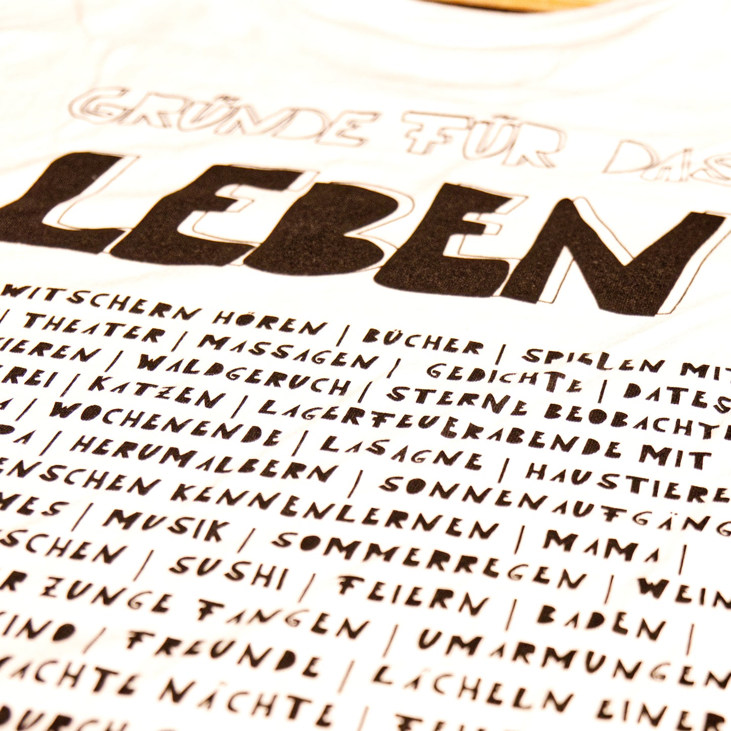 Nahaufnahme des Motivs Gründe für das Leben auf einem weißen Shirt, gedruckt mit schwarzer Farbe.
