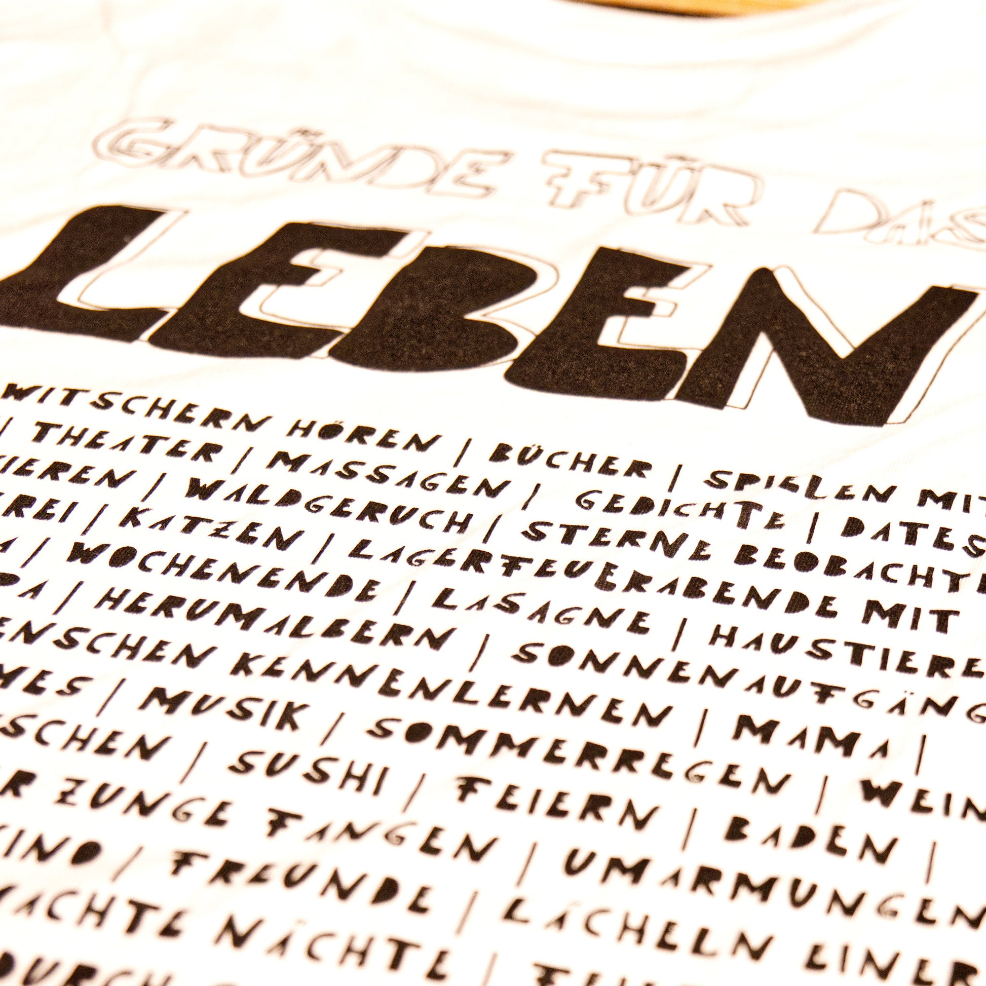 Nahaufnahme des Motivs Gründe für das Leben auf einem weißen Shirt, gedruckt mit schwarzer Farbe.