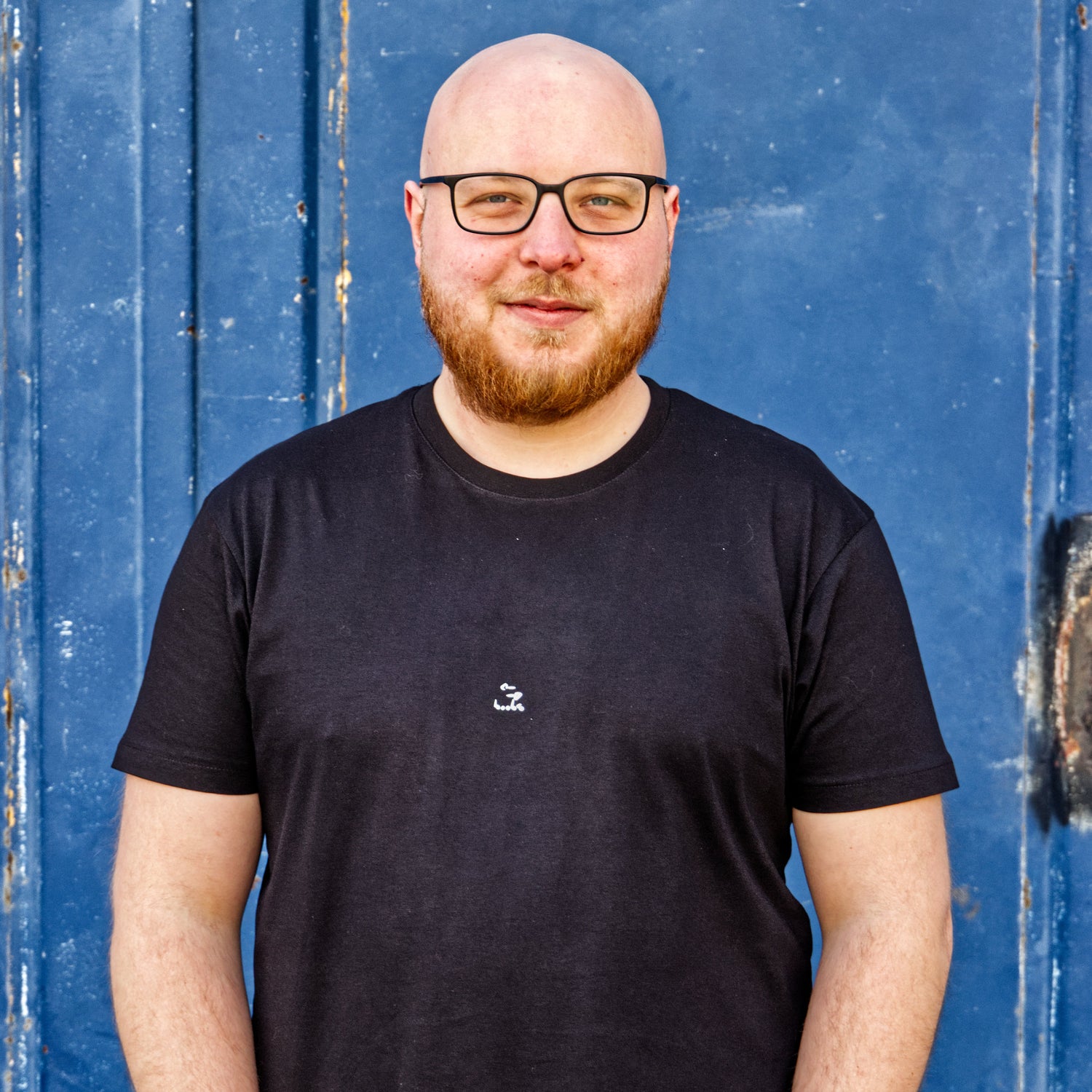 Shopinhaber mit handgedrucktem Shirt vor blauem Hintergrund